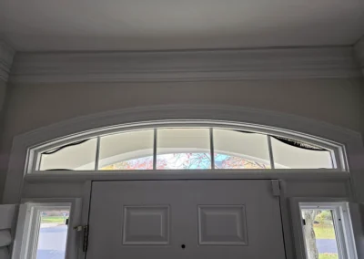 Arched transom window above a front door, viewed from inside the home.