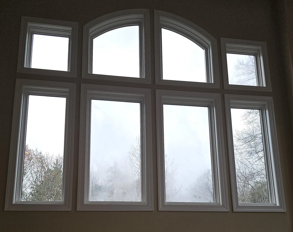Tall window group with an arched center and cloudy glass, viewed from indoors.