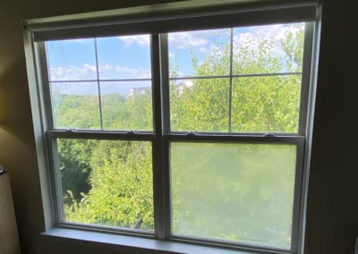 Double-hung window with a cloudy lower pane beside clear panes.