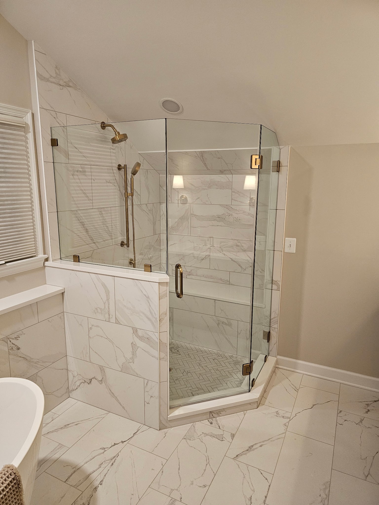 Custom glass shower enclosure with gold-tone hardware.