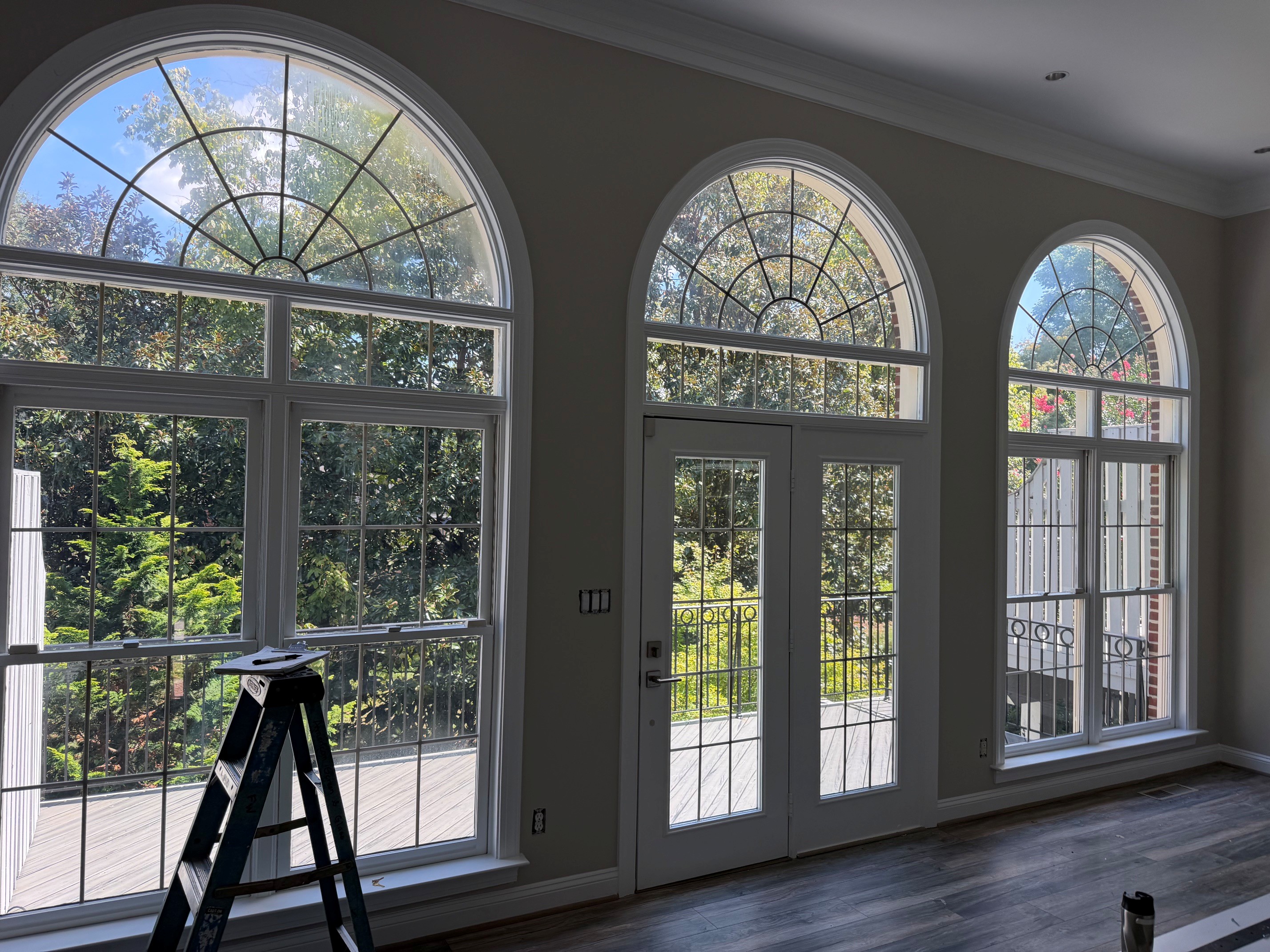 Tall arched windows and glass French doors overlooking a leafy garden, from the American Screen & Glass portfolio.