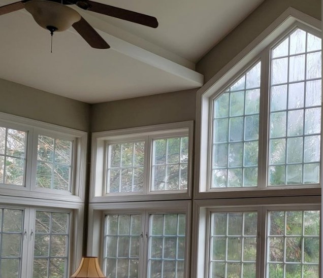 Hazy glass in a tall white-framed great-room window wall before glass replacement.