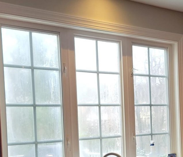 Cloudy glass in white-framed kitchen windows before glass replacement.