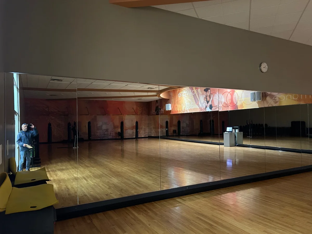 Long mirror wall above the wood floor of a dance studio