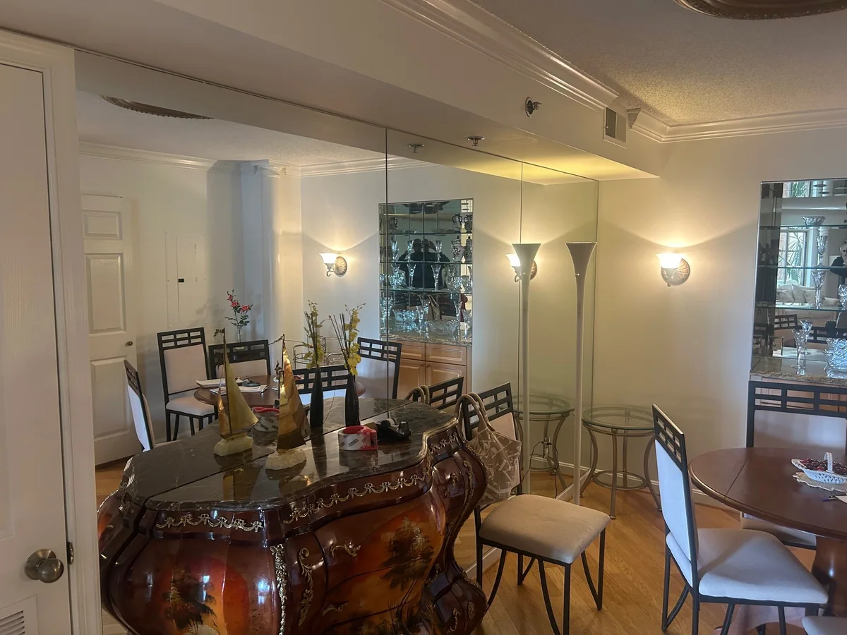 Large wall mirrors reflecting a dining room and chandelier