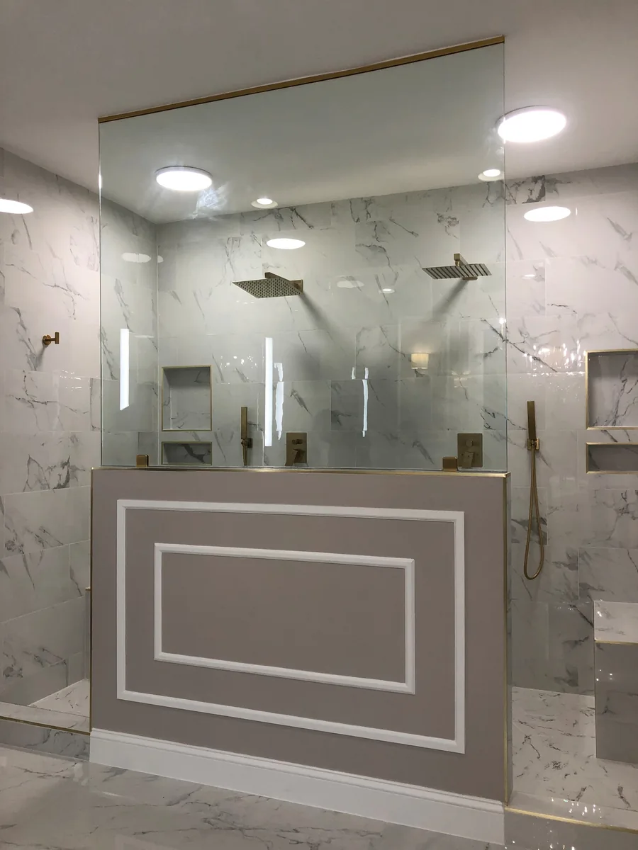 Wide bathroom vanity mirror beneath lights and above a sink.