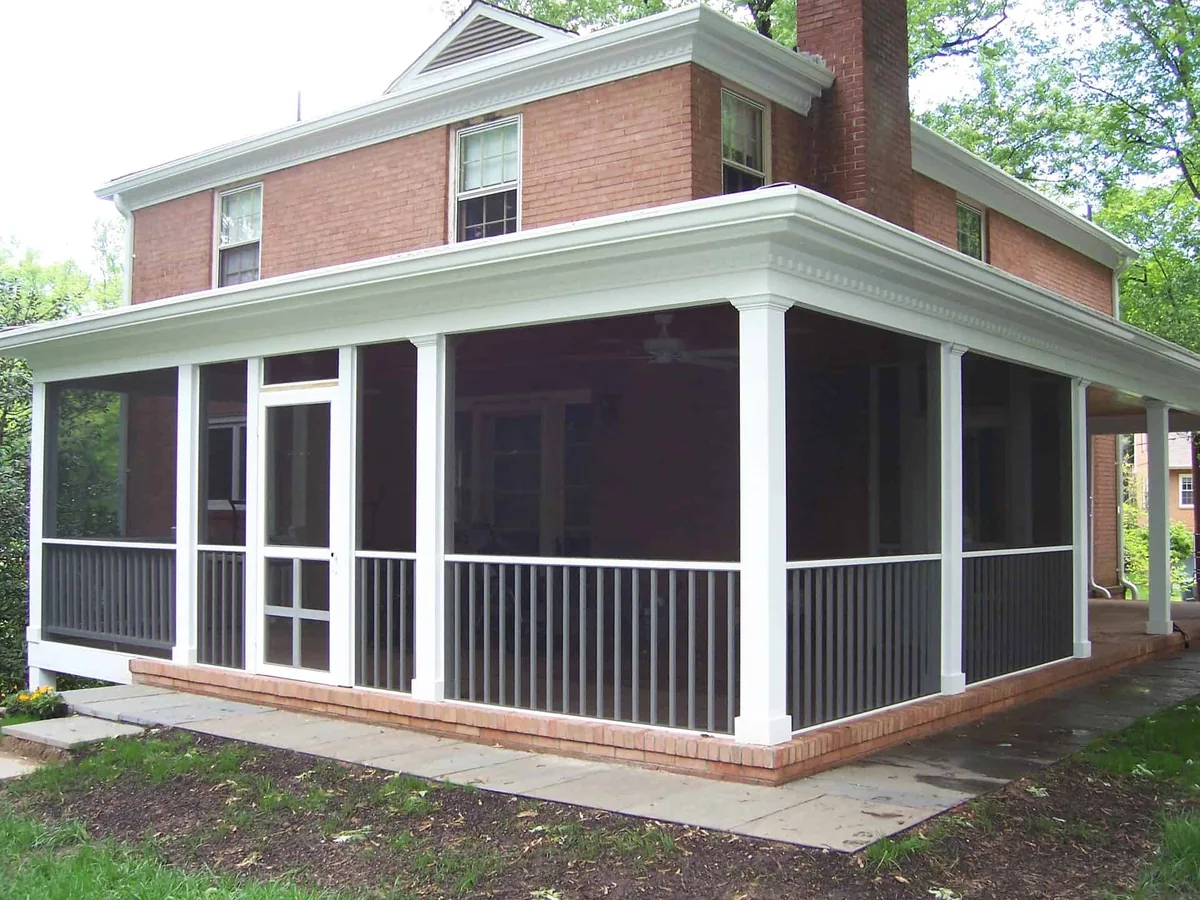 White-framed wraparound screened porch on a brick home.