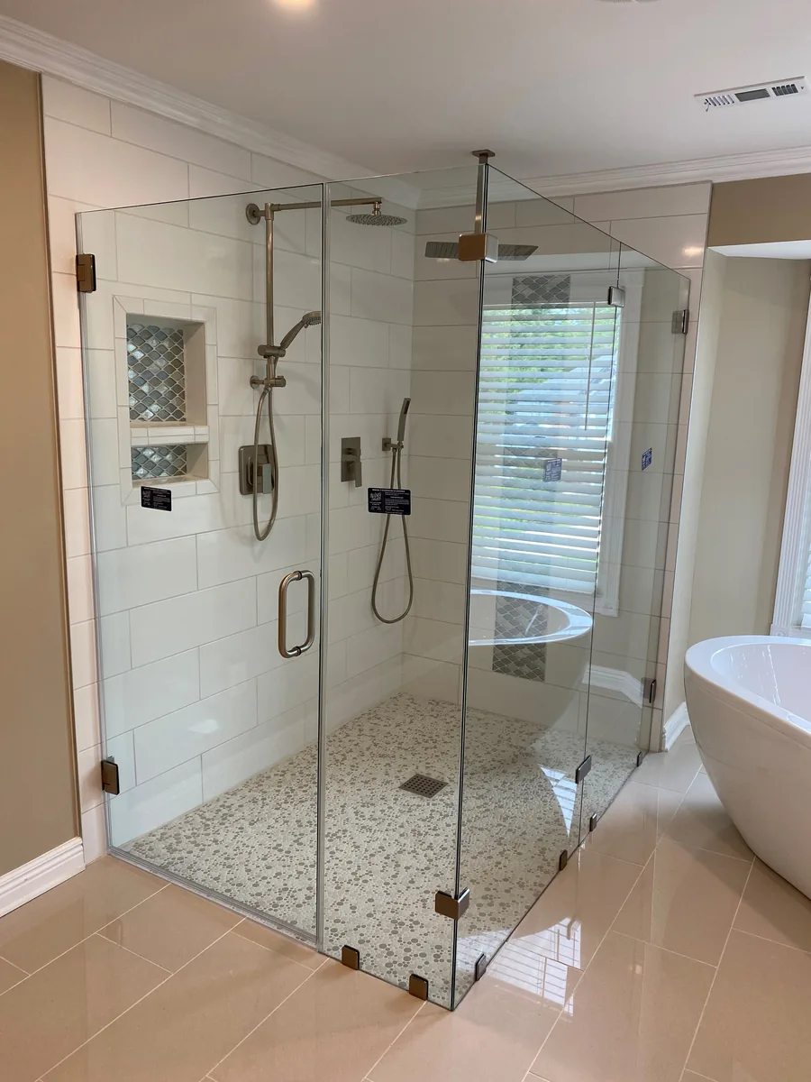 Clear corner shower enclosure with a rain shower, white wall tile, and decorative blue tile niches.