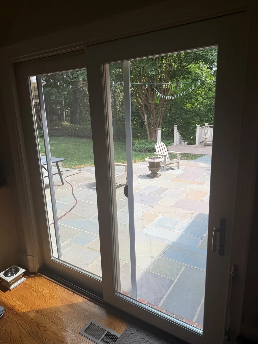 White sliding glass doors looking onto a stone patio.