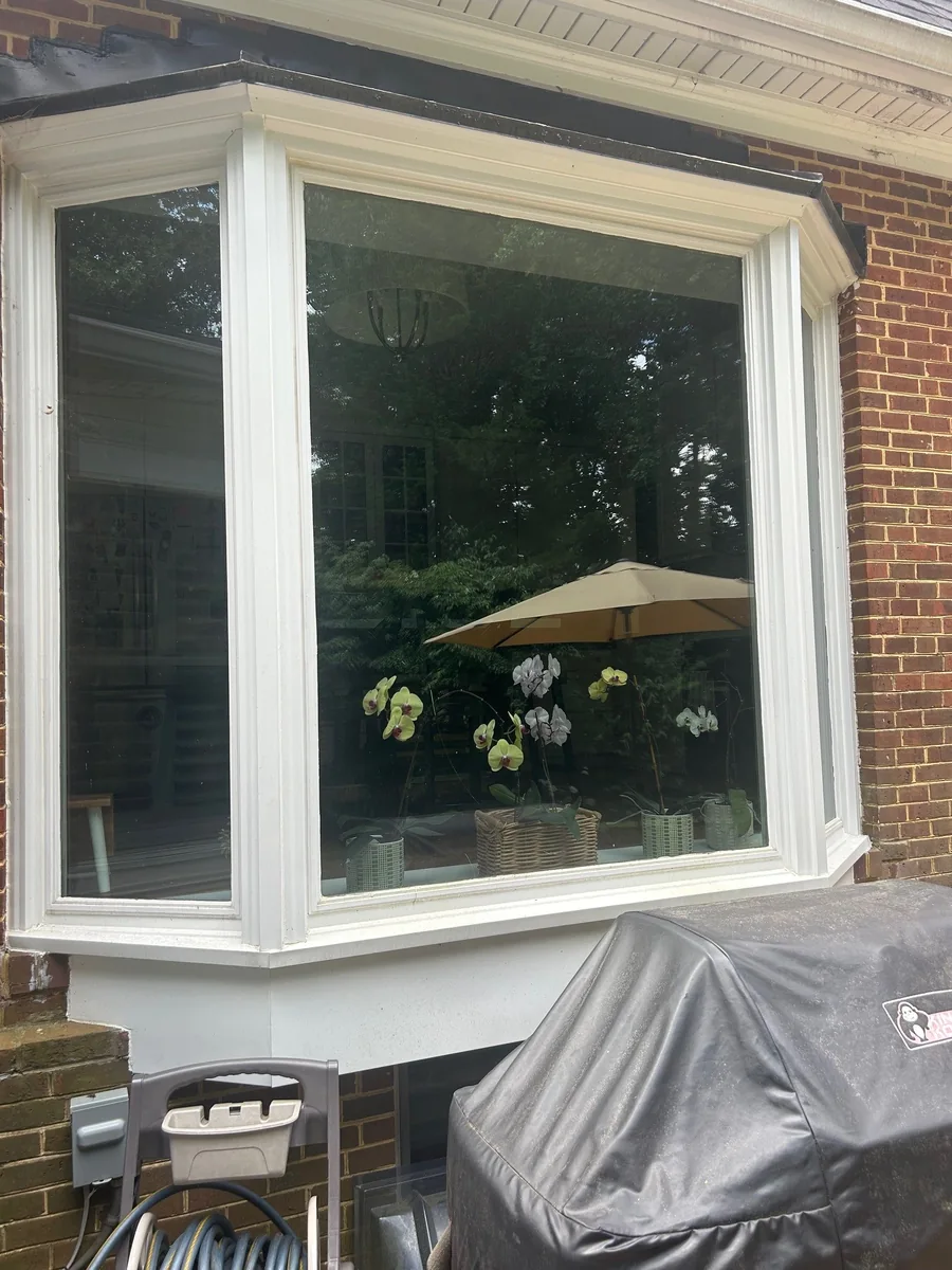 White-framed bay window on a brick home overlooking a patio.