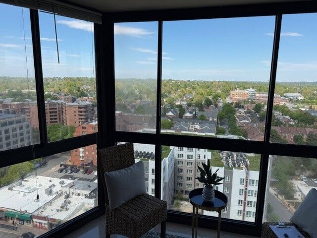 A glazed high-rise balcony corner overlooking the surrounding neighborhood