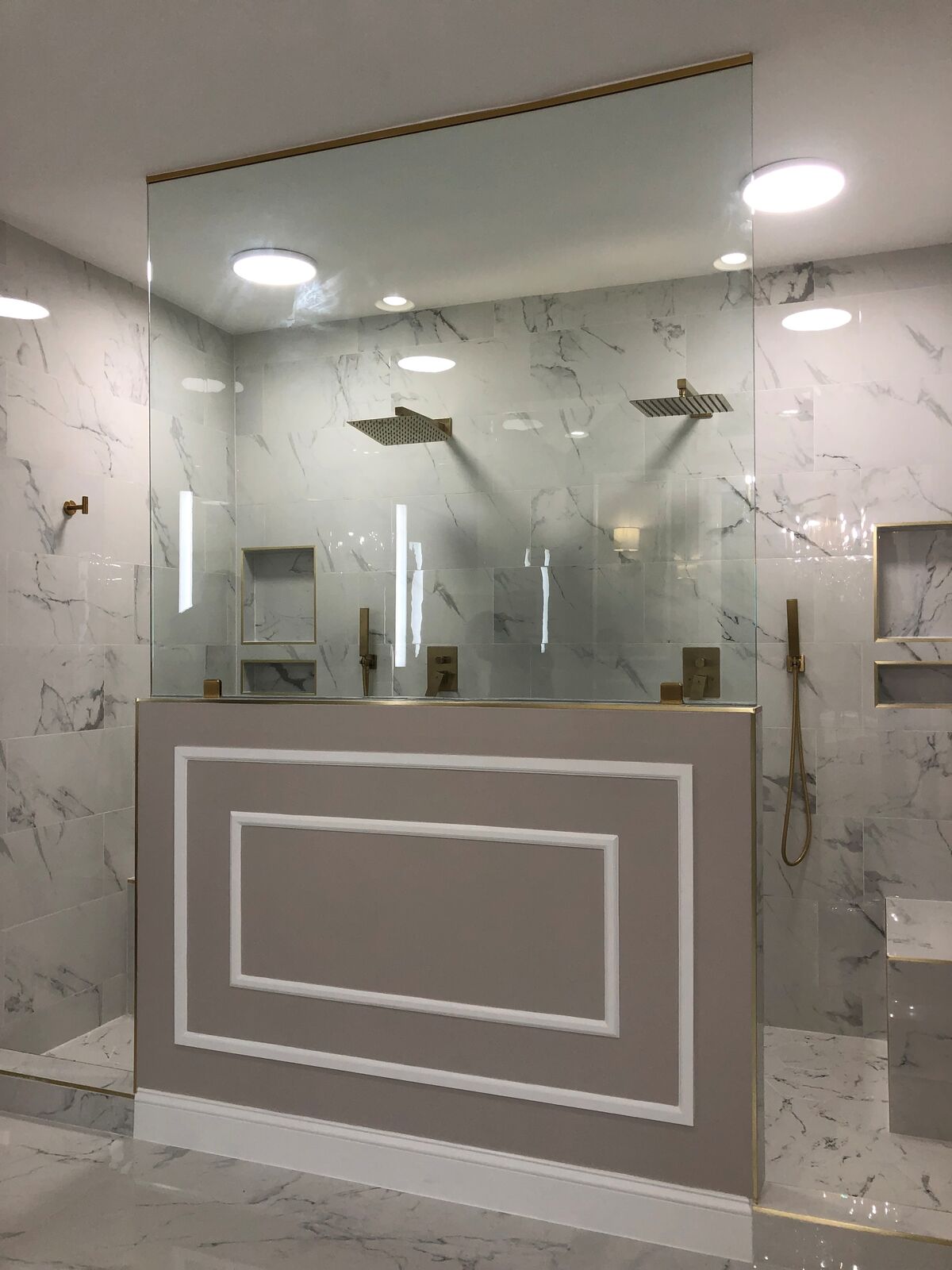 A frameless glass shower set on a tiled half wall
