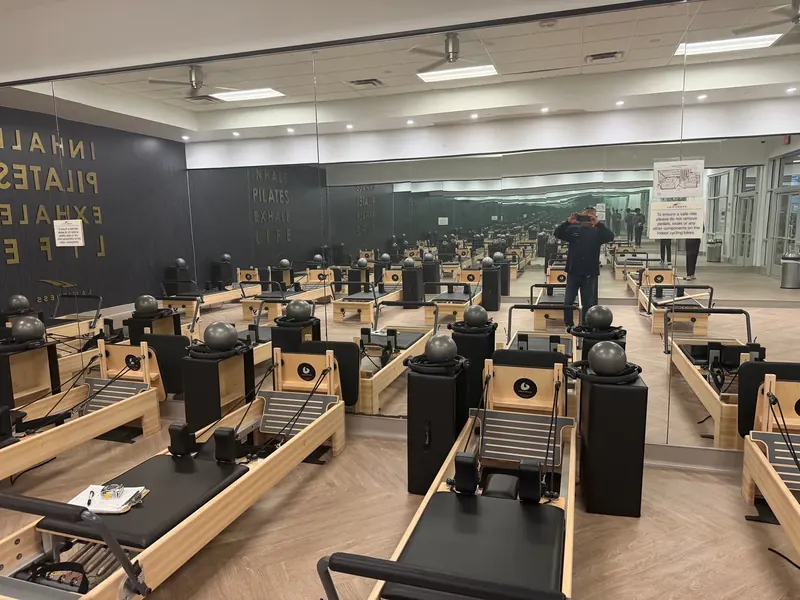 A full-width mirror wall reflects Pilates equipment.