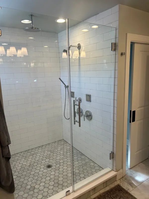 A clear shower door encloses a white subway-tiled shower.