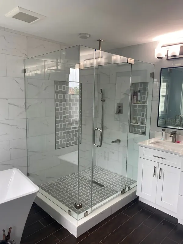 Corner glass shower beside a freestanding tub and white vanity.