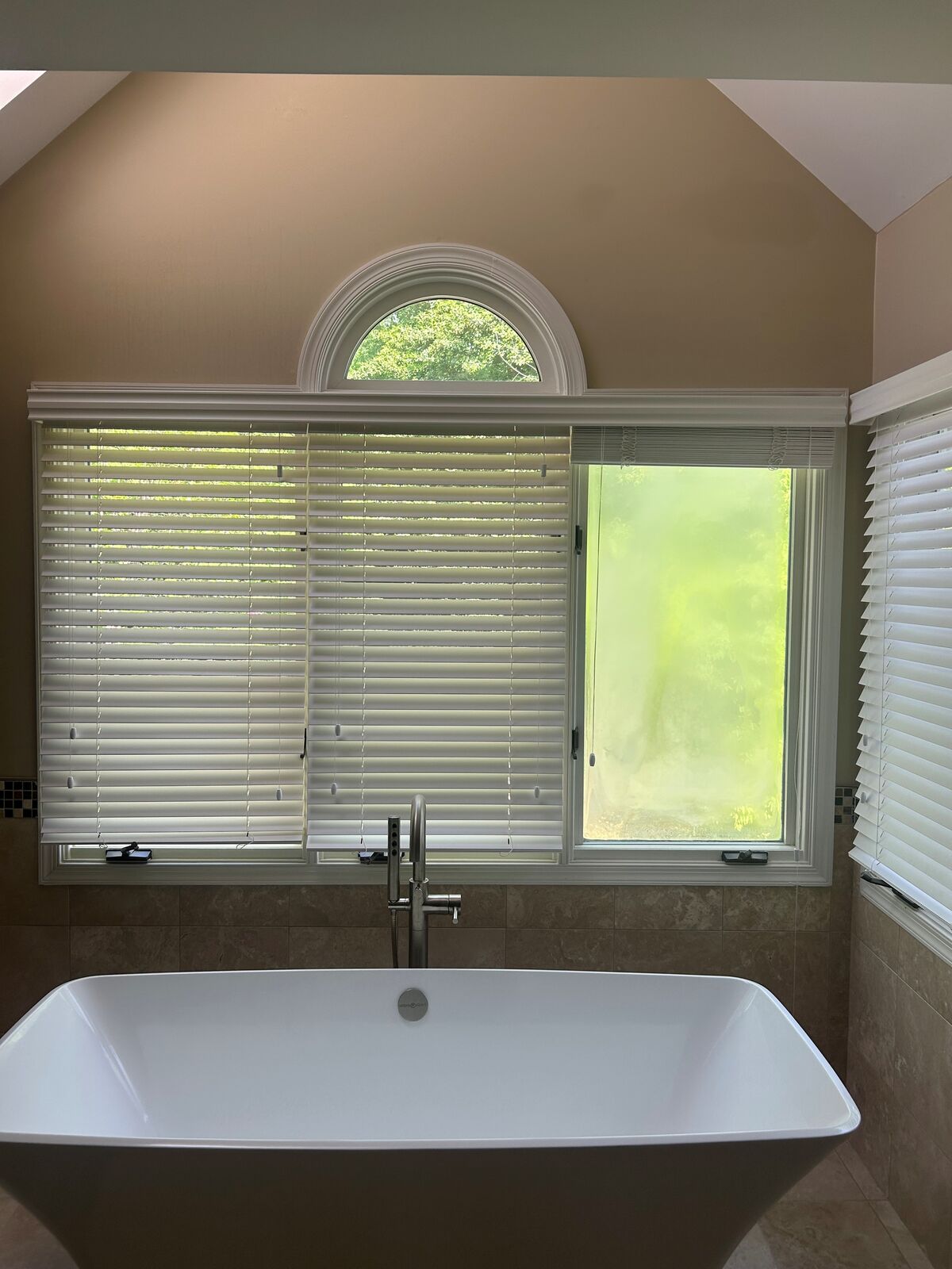 Two bathroom windows above a soaking tub, beneath a half-round transom