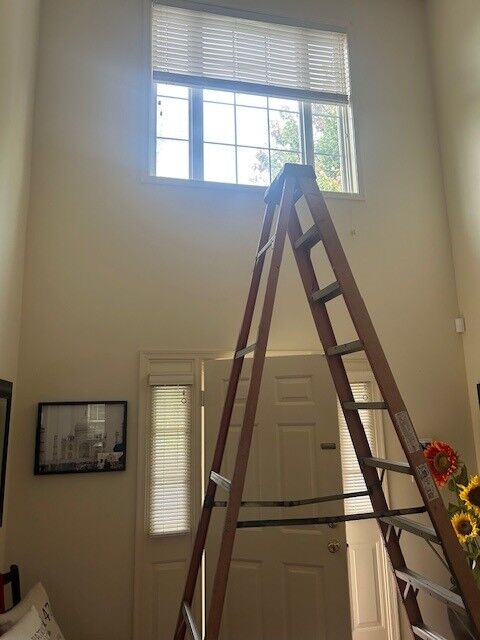 A tall ladder set up beneath a high two-story foyer window