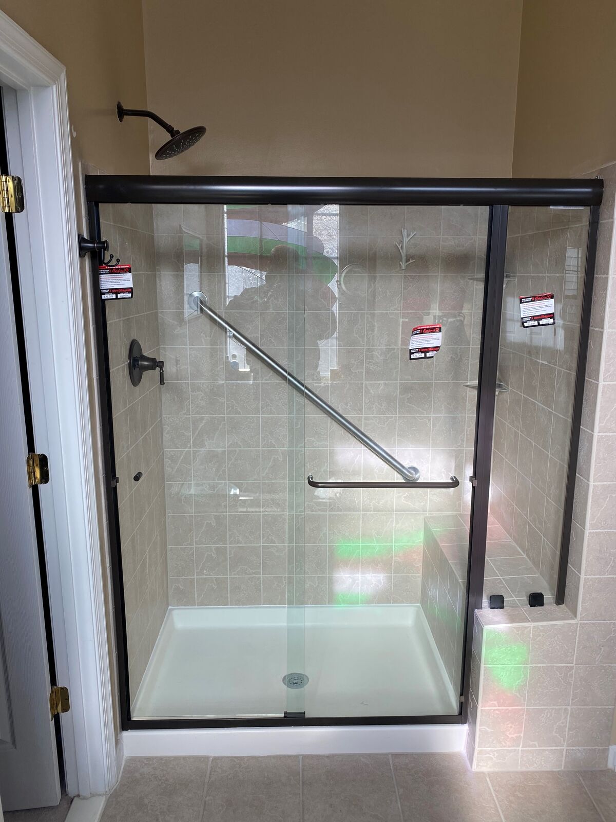 A black-framed shower enclosure with a wall-mounted accessibility support rail inside
