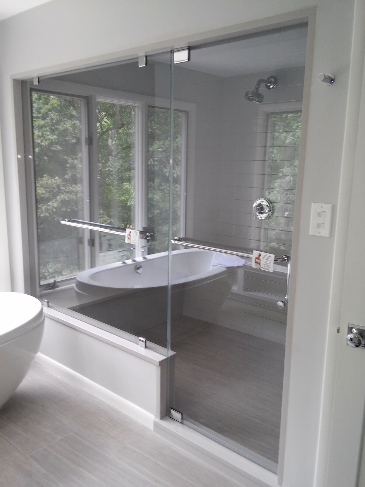 Full-height clear shower glass beside a freestanding bathtub, without a visible vent panel