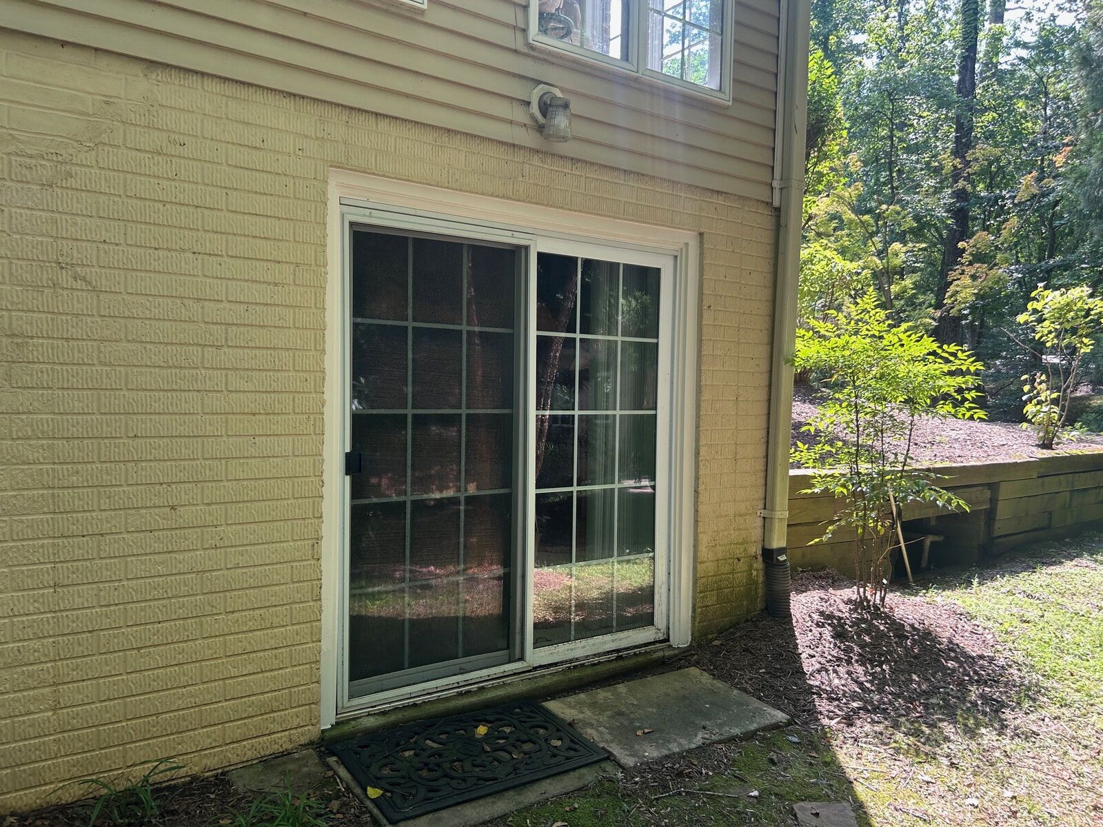 A sliding patio door with grids set in a painted brick wall