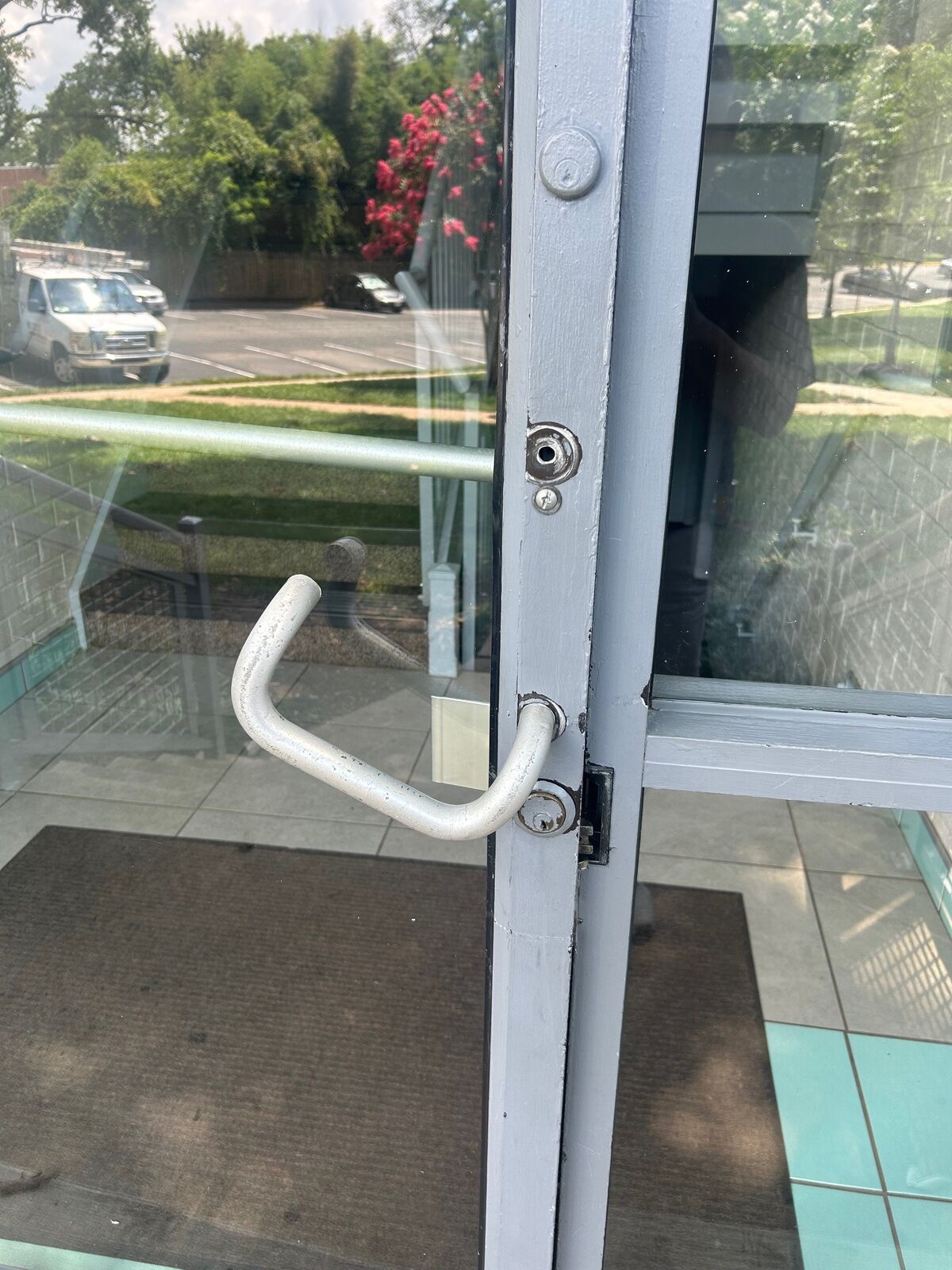 Bent pull hardware and visible damage near the lock on a glass entry door