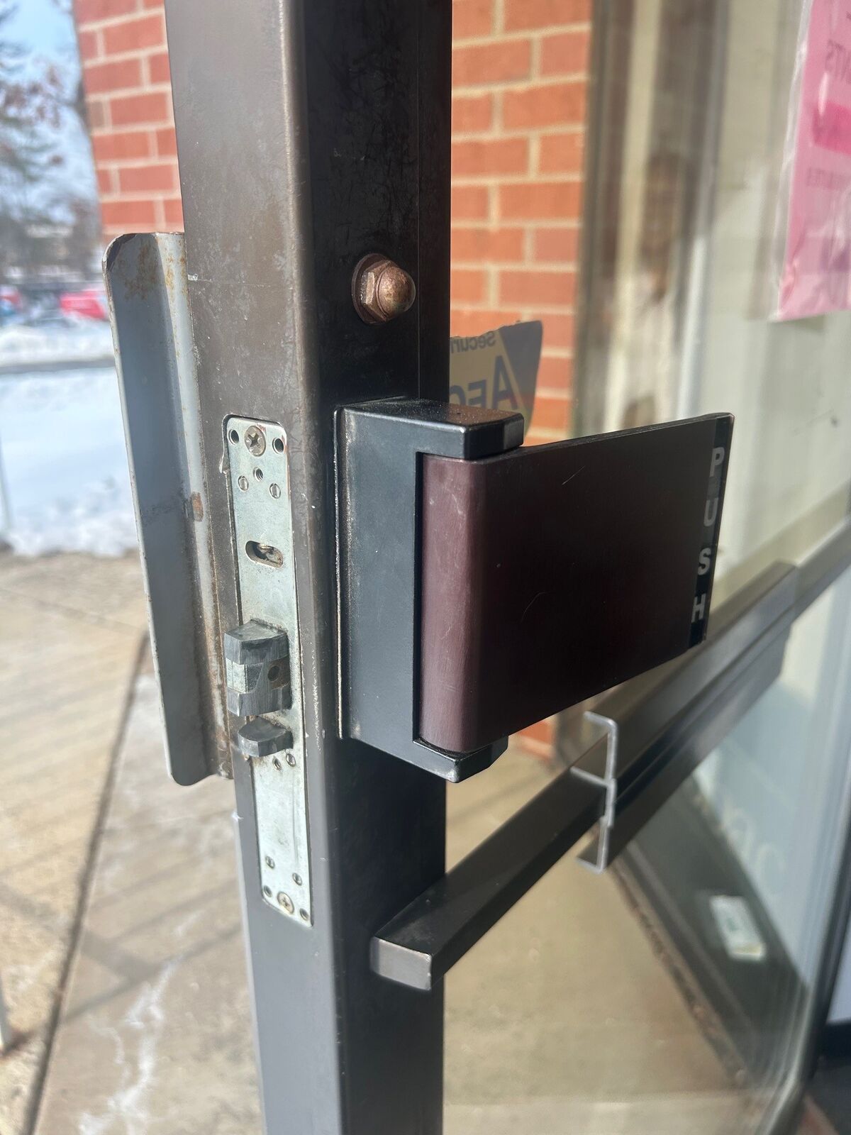 Close-up of a commercial glass door latch and push hardware