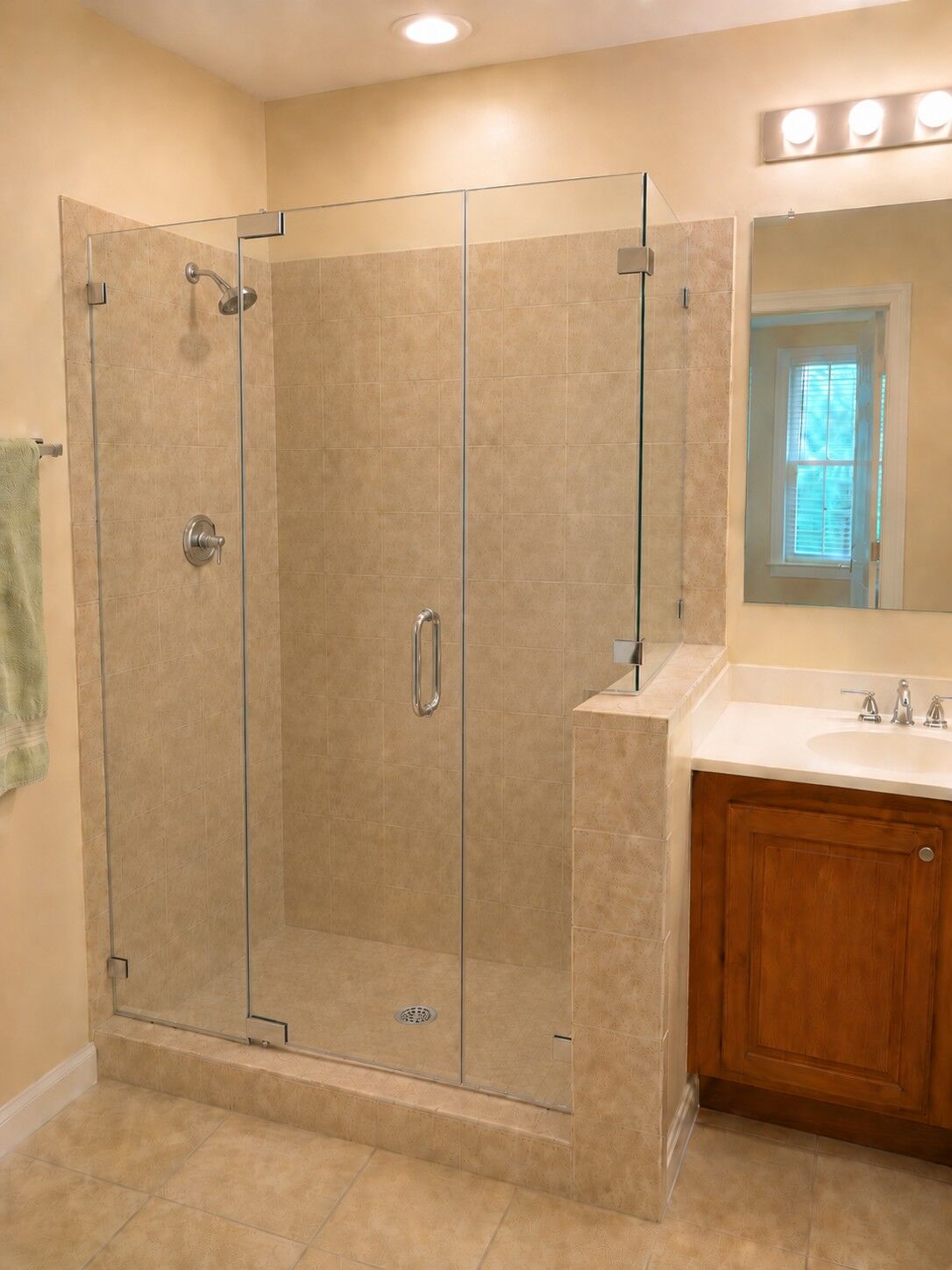 A frameless glass shower enclosure beside a wood bathroom vanity