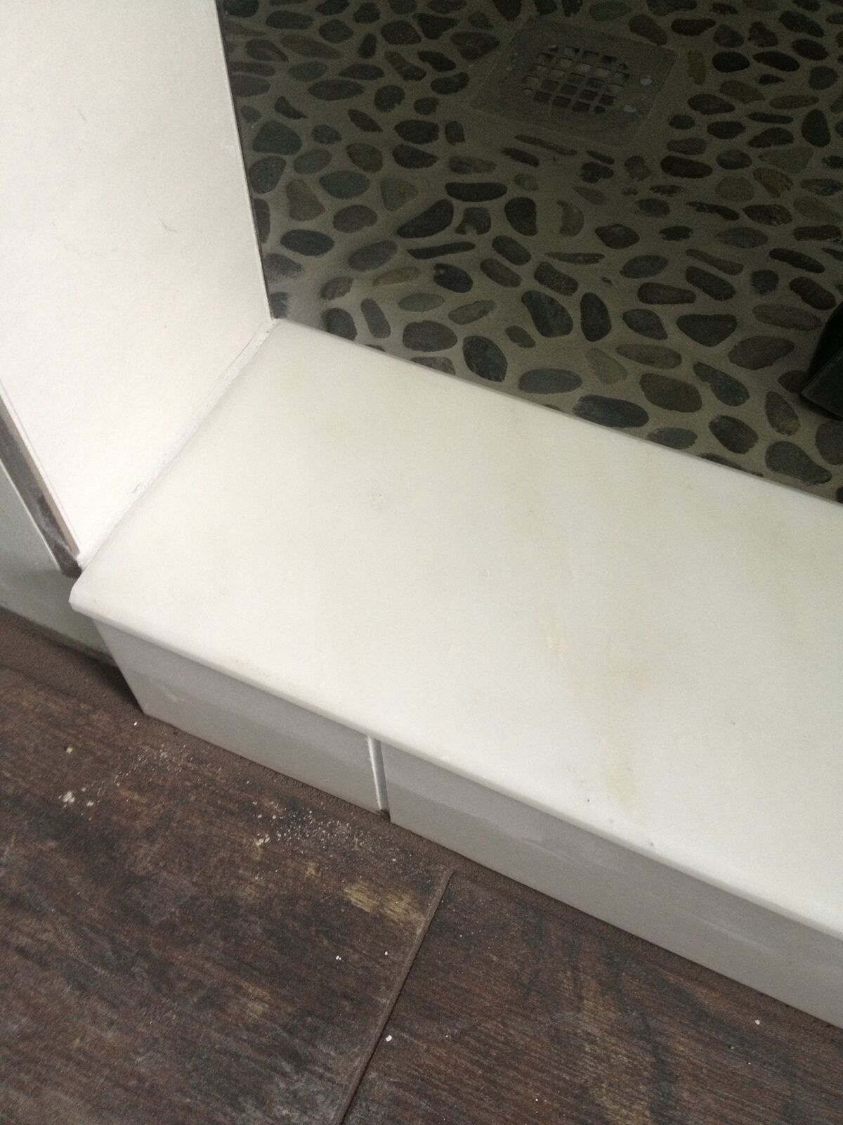 A close-up of a white shower threshold at the base of the shower