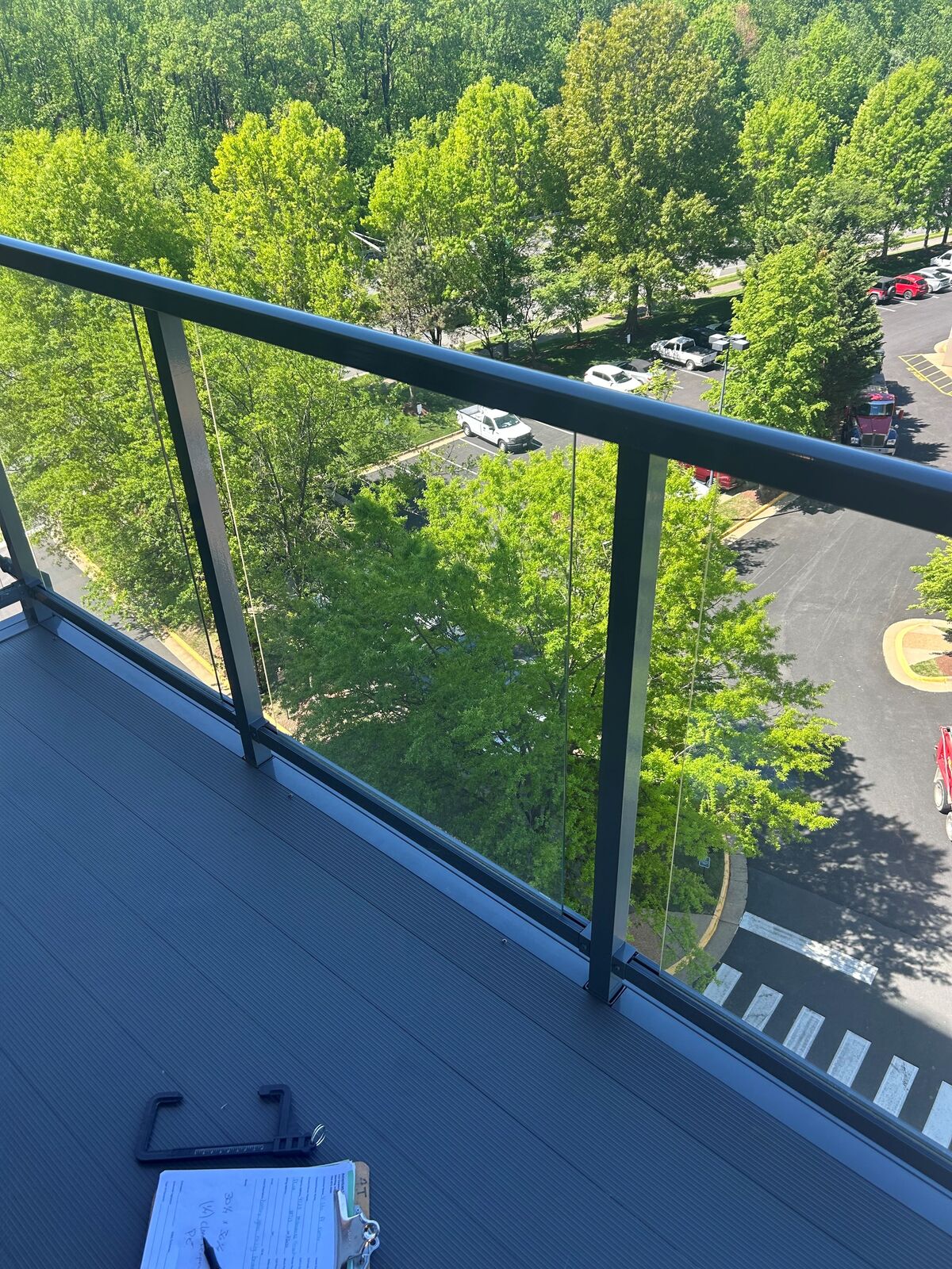 A glass balcony railing with trees beyond it