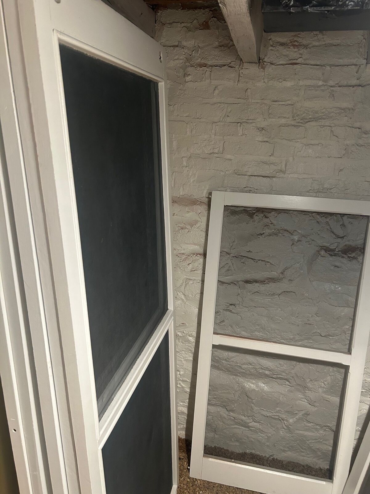 Tall screen panels and screen frames standing against a basement wall