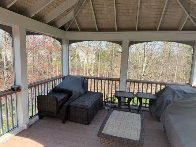 A furnished screened porch with a wood ceiling and a view to trees