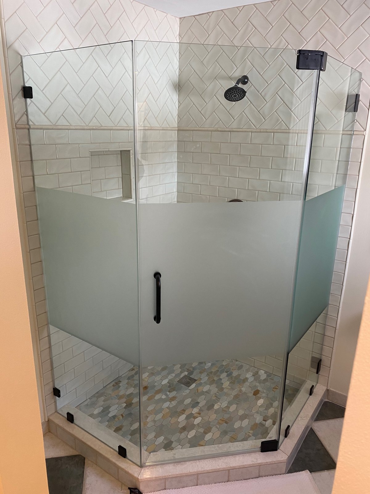 A frameless neo-angle shower with a wide frosted privacy band across all three panels and black hardware