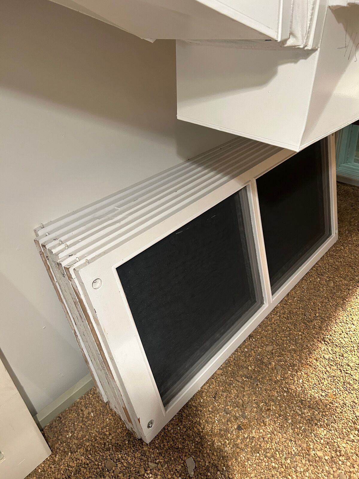A stack of white window screens leaning against a wall